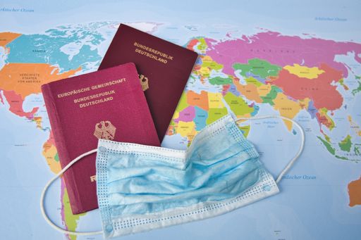 close up shot of two German passports on a world map with a corona breath mask, Germany