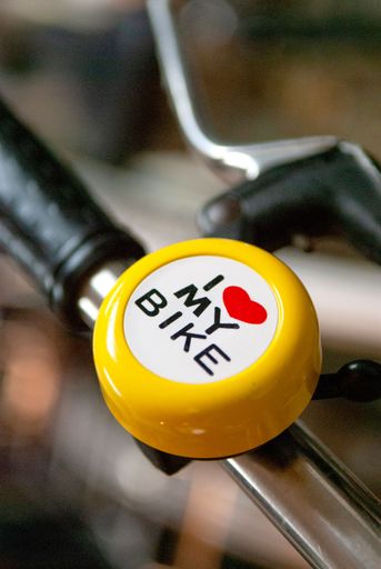 A closeup view of a yellow bike bell with ''I love my bike'' written on it