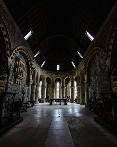 The interior of an ancient stone cathedral with pillars, arches, and large windows in Scotland, UK
