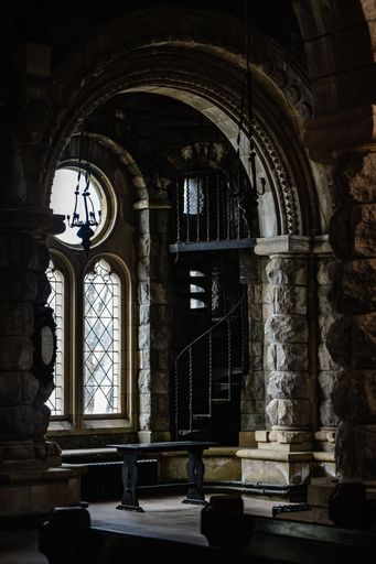 The interior of an ancient European stone cathedral with pillars, stairs, arches, and large windows in Scotland, UK