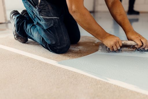 A closeup shot of a worker applying grey epoxy resin on the floor