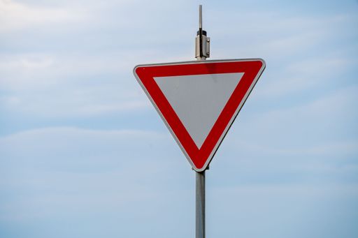 A blank triangle warning road sign against the blue sky