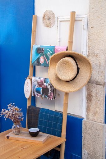 The vertical shot of magazines on a wooden stand with a straw hat in a cafe shop