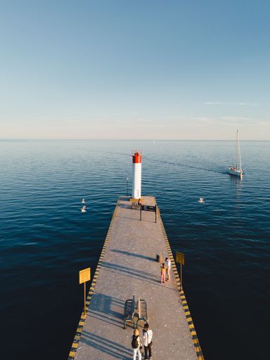 A vertical drone shot of Whitby lighthouse and pier in Ontario, Canada, during golden hour