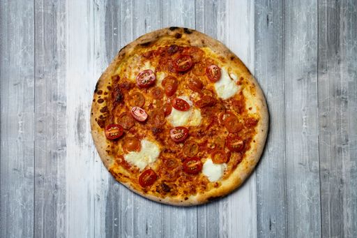 A top view of a delicious pizza with slices of tomatoes and mozzarella cheese