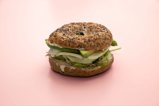 A closeup shot of an avocado bagel with mozzarella and lettuce