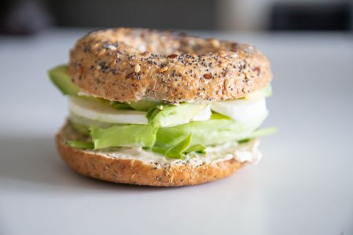 A closeup shot of an avocado bagel with mozzarella and lettuce