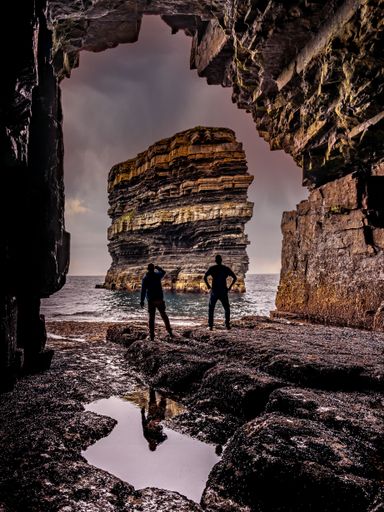 A vertical shot of young boys walking near the sea at sunset