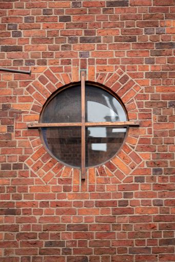 A vertical shot of a round window in a brick wall
