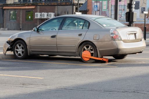 A closeup shot of a wheel lock clamp on a car in a downtown Morgantown, WV parking lot