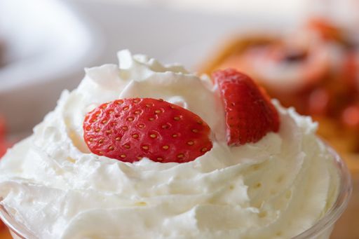 A  closeup selective focus shot of whipped cream with fresh strawberries