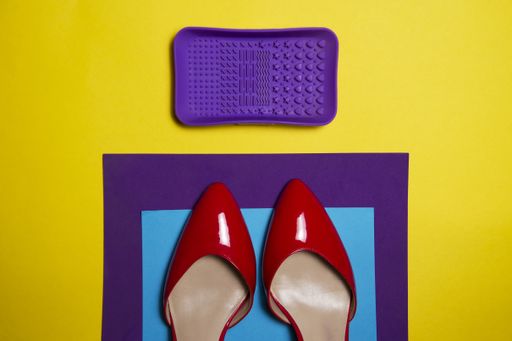 An overhead shot of vivid red woman shoes on a yellow background with a purple and blue carpet