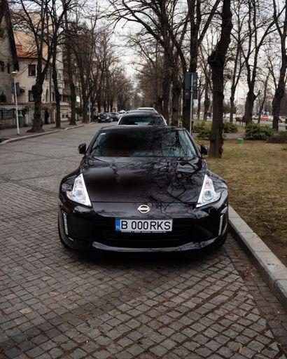 A black Nissan sedan parked on a city street, its sleek lines and glossy finish shining in the sun