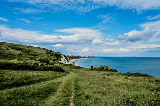 An idyllic pathway is seen winding through lush green grass on British coast