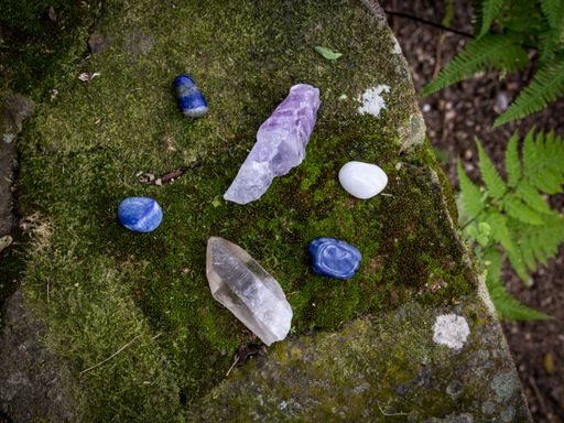 A top view of a bunch of crystals and quartz stones on a mossy rock surface