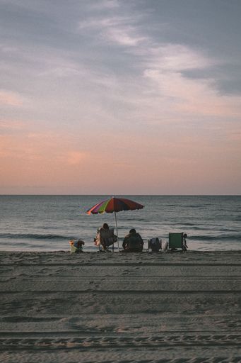 A couple resting on a sandy beach on the sunset