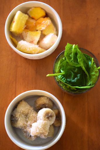 A vertical top view of the bowls with cut banans, green leaves and lemon slices with sugar on the wooden table