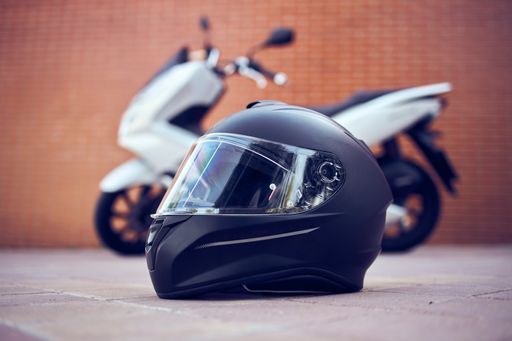 A closeup of a  black helmet with a white motorcycle on the background