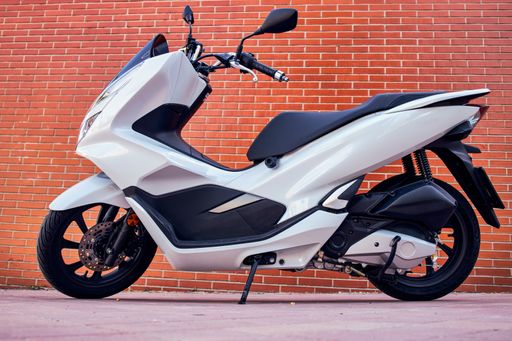 A white motorbike with rusty White motorcycle with a brick wall background