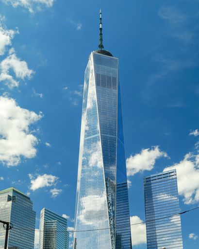 A vertical low angle of beautiful blue sky and clouds reflecting on the World Trade Center Freedom Tower