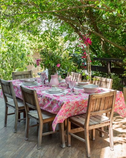 A vertical shot of wooden chairs and a table with utensils on it in a garden under the sunlight