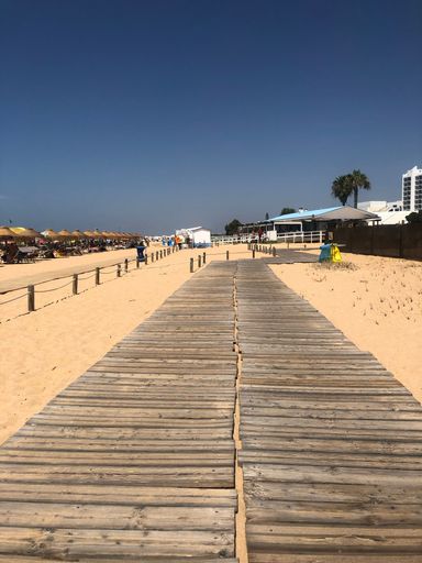 A vertical shot of a wooden way on a sandy beach near the resort