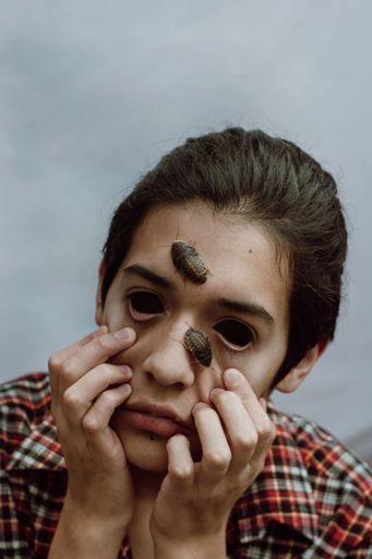 boy and cockroaches on his face, without eyes and desolate
