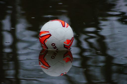 A missed soccer floats on the river Nidda with beautiful reflections. A splash of color on a rainy January day.