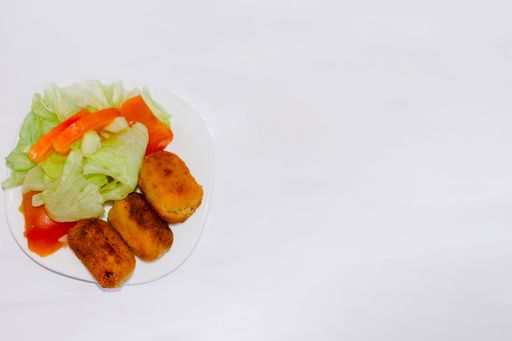 A top view of Croquettes with vegetables in a plate isolated on a white background