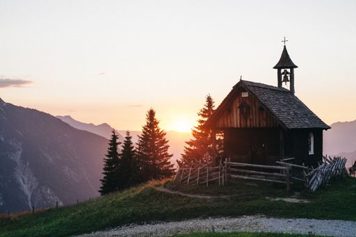 A beautiful shot of a small isolated wooden chapel at the edge of a cliff and the sunset in the background