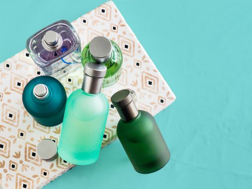 A top view of colorful bottles of perfume on a napkin on a blue surface