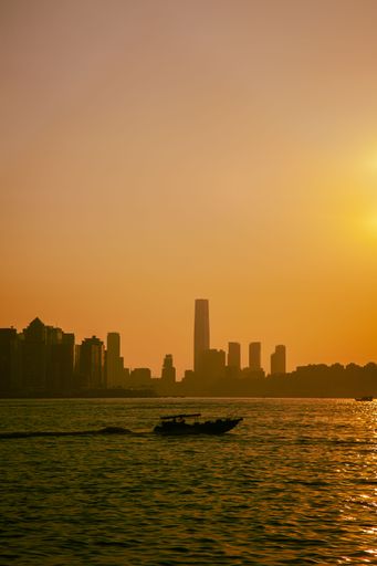 A vertical shot of a small boat sailing in the lake at sunset in Hong Kong