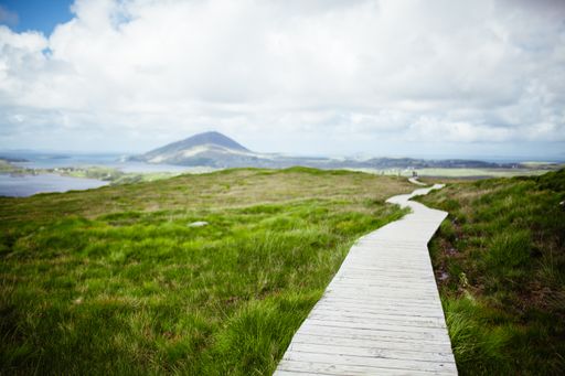 A beautiful shot a road made of wooden desks in the middle of a valley and the cloudy sky in the background
