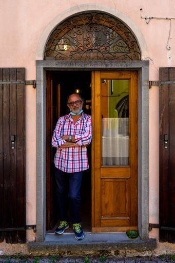 Portrait of an Italian man standing in the door opening of his house. Wearing a mask due to Covid-19.