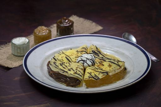 A closeup shot of delicious pancakes filled with chocolate, jam and caramel milk