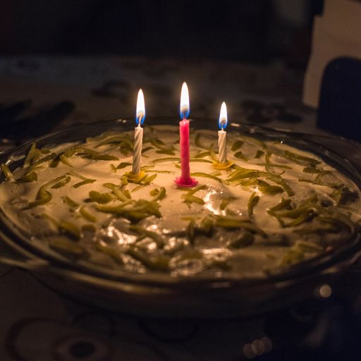 A selective focus shot of a delicious homemade cake with three candles