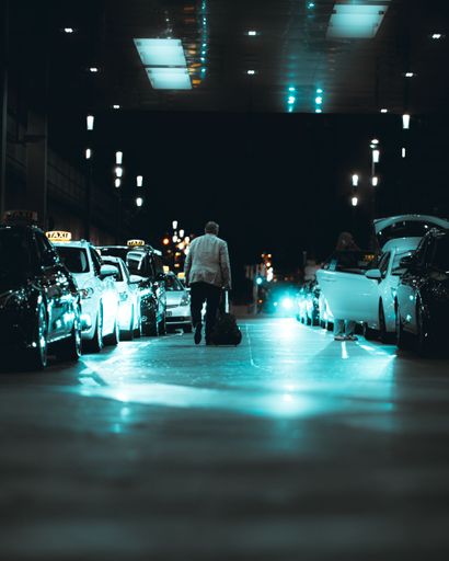 An old man walking with travel bag going to take a taxi at night