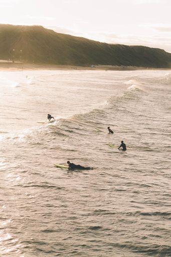 A vertical shot of the Saltburn beach with surfers in the sea during golden hour