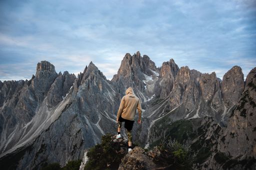 The Italian Dolomites in the early morning at sunrise, hugged by mist and clouds. Rolling green hills and sheer white cliffs, blue skies