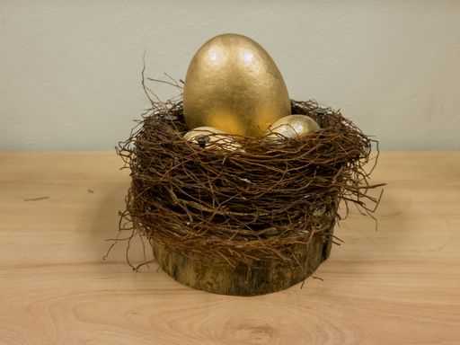 A closeup shot of golden egg in a nest on the table