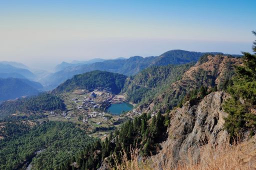 A beautiful view of a lake surrounded by trees and mountains in Nainital, India