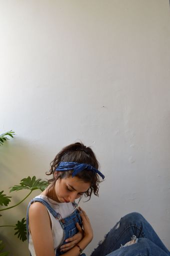 A vertical shot of a confident young brunette woman sitting on the floor and holding herself - self love concept