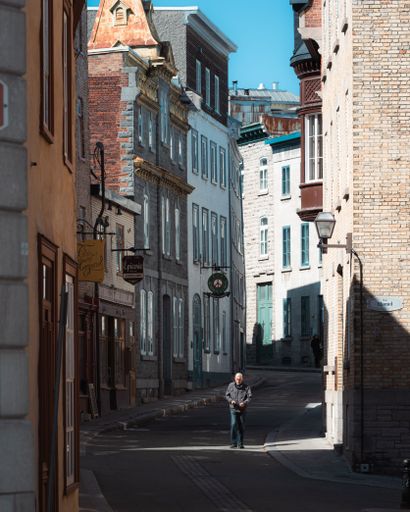 A vertical shot of a Lonely man walking in empty street between old buildings