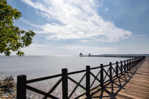 An old wooden pier in front of the see with a beautiful cloudy sky in the background