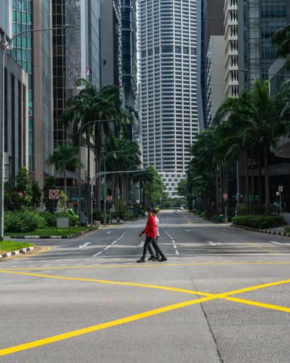 Two men waring mask crossing the street at the Central Business District , Singapore. Empty city