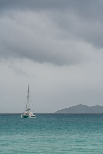 A vertical shot of a single boat floating in the sea on a rainy day
