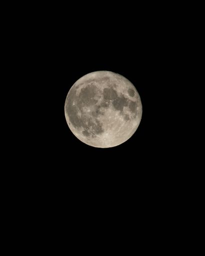 A vertical shot of a full moon isolated on a dark sky