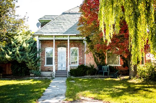 The front facade of the brick house surrounded by colorful trees on a sunny day