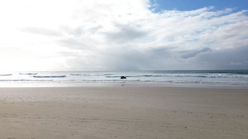 An empty scenic beach under a cloudy sky