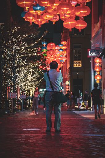 A vertical shot of a man from behind surrounded by red lanterns